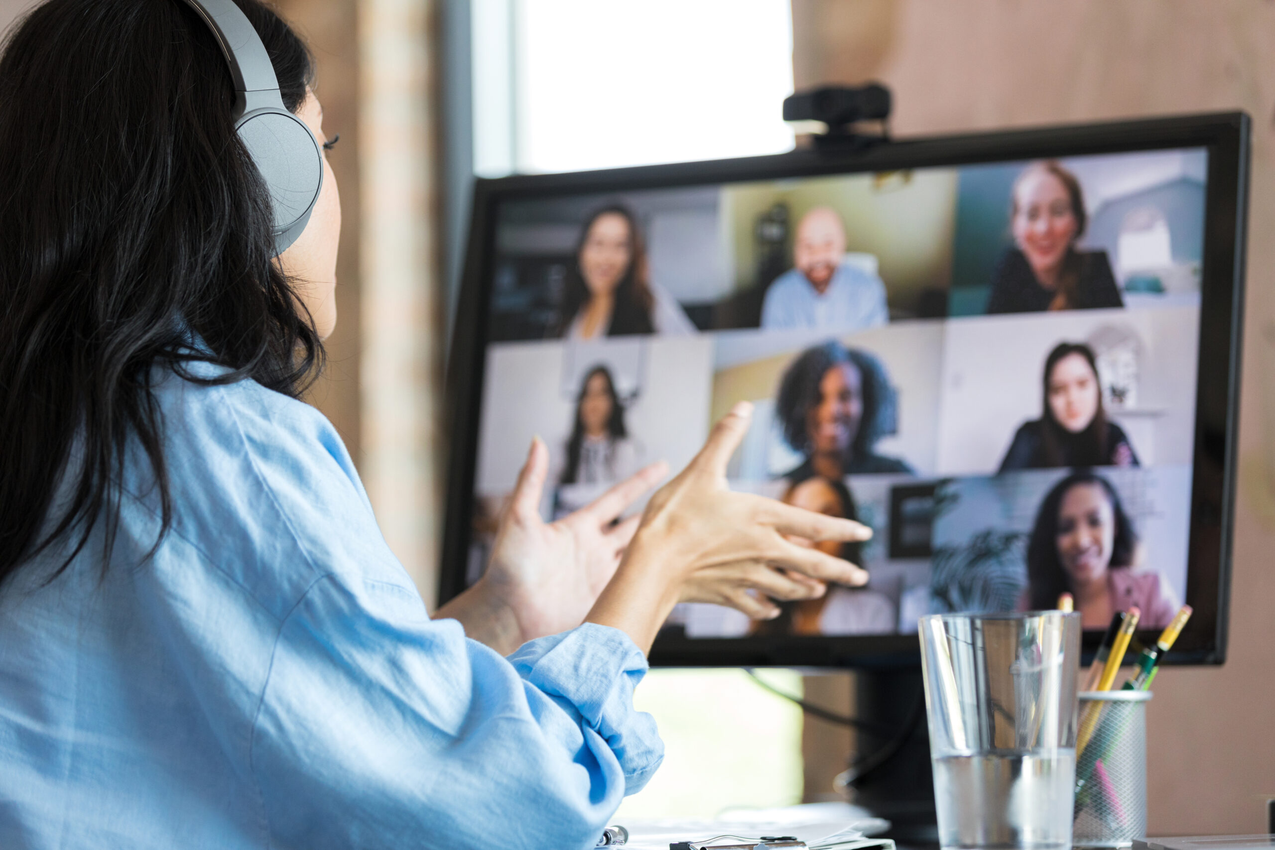 Unrecognizable woman gestures during video conference with co-workers